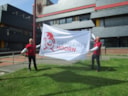 Burgemeester en wethouder hijsen vlag nieuw logo
