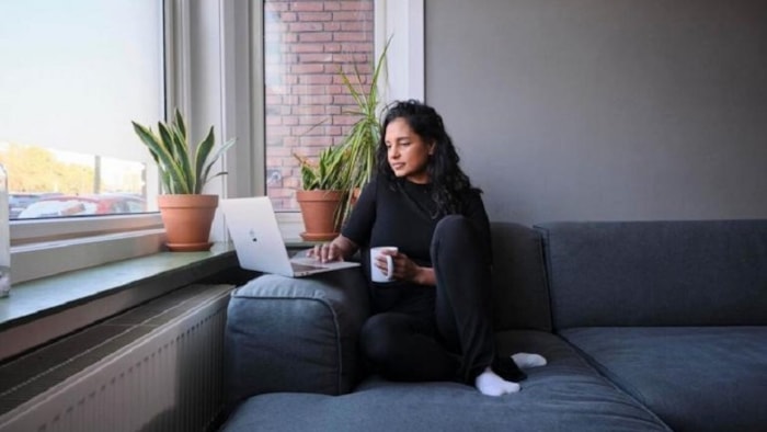 Vrouw zit op bank met laptop