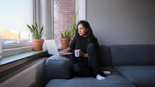 Vrouw zit op bank met laptop