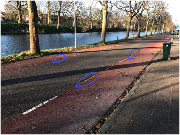 Kraters in rood asfalt zijn gevaar voor verkeersveiligheid fietsers