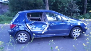 De zwaar beschadigde blauwe auto