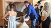Wethouder Simon Broersma pakt samen met twee leerlingen uit groep 8 van basisschool Het Fluitschip het model van het fluitschip De Risdam  uit (Foto Henk Sas)