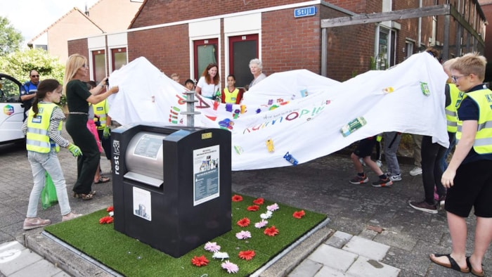 Onthulling bloementapijt bij afvalcontainer