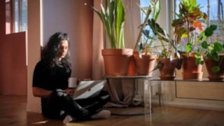 Vrouw zit in de kamer op de grond achter de laptop