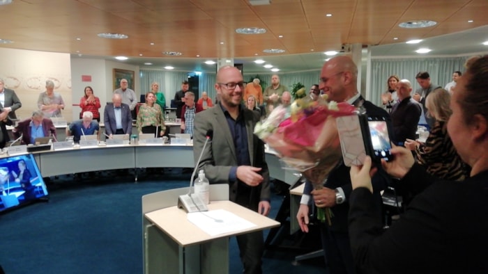 Nieuw commissielid Niels Bakker ontvangt bloemen