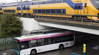 Bus onder spoorbrug met trein