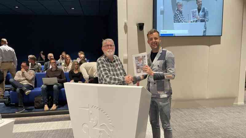 Sjaak Grosthuizen biedt wethouder Axel Boomgaars zijn gebundelde columns aan